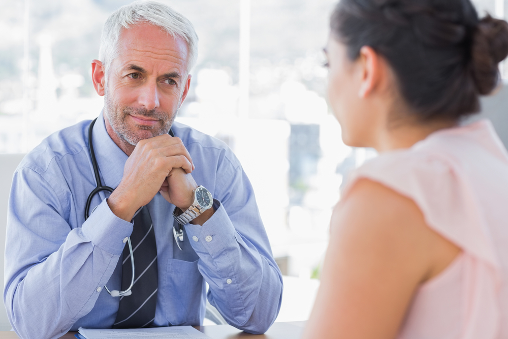 Serious doctor listening to patient explaining her painful in his office Serious doctor listening to patient explaining her painful in his office